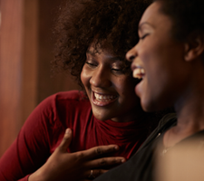 Two woman smiling and hugging.